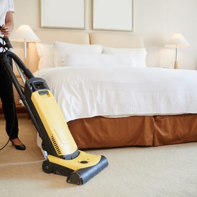 Maid cleaning carpet in hotel room